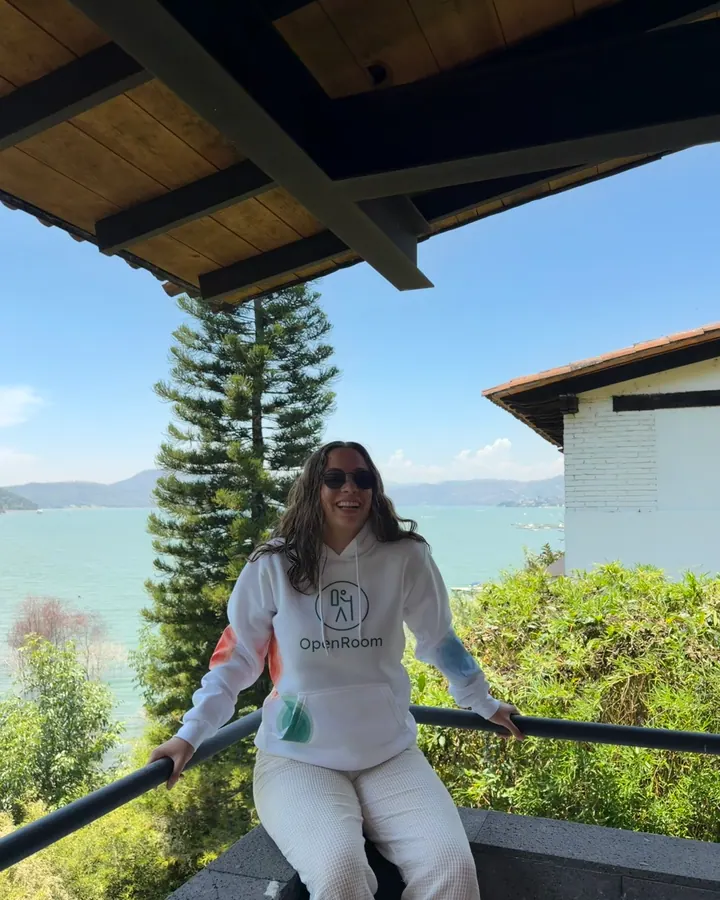 OpenRoom brand ambassador wearing a hoodie on a lake-view balcony