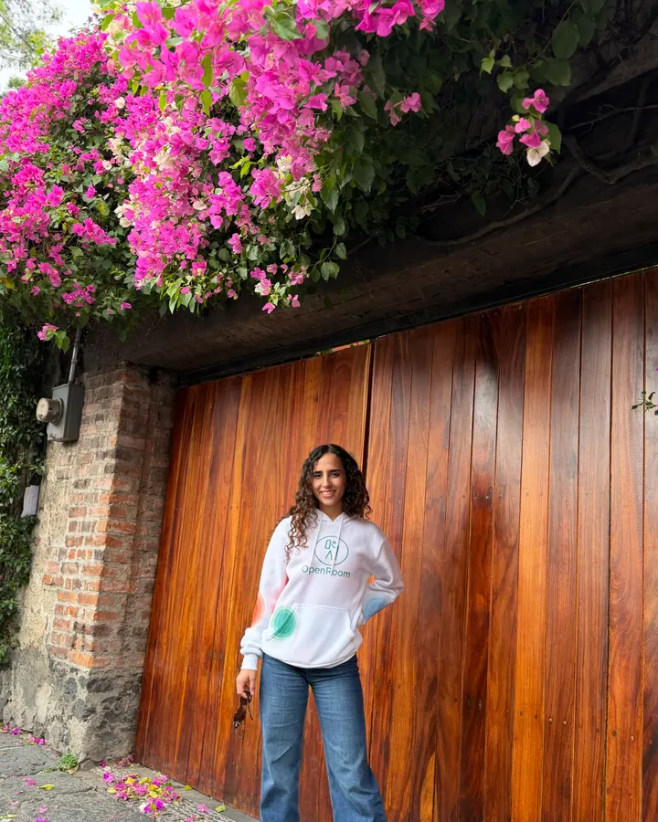 OpenRoom brand ambassador standing in front of a wood door and pink flowers
